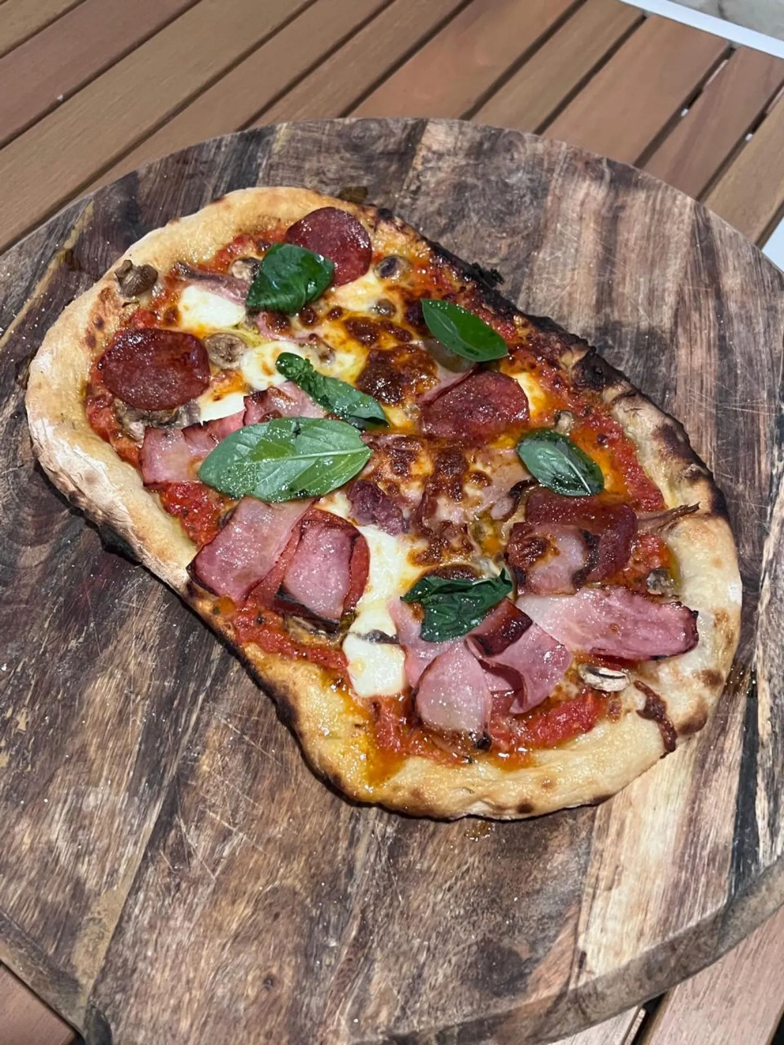 A cooked pizza fresh from the oven on a wooden board