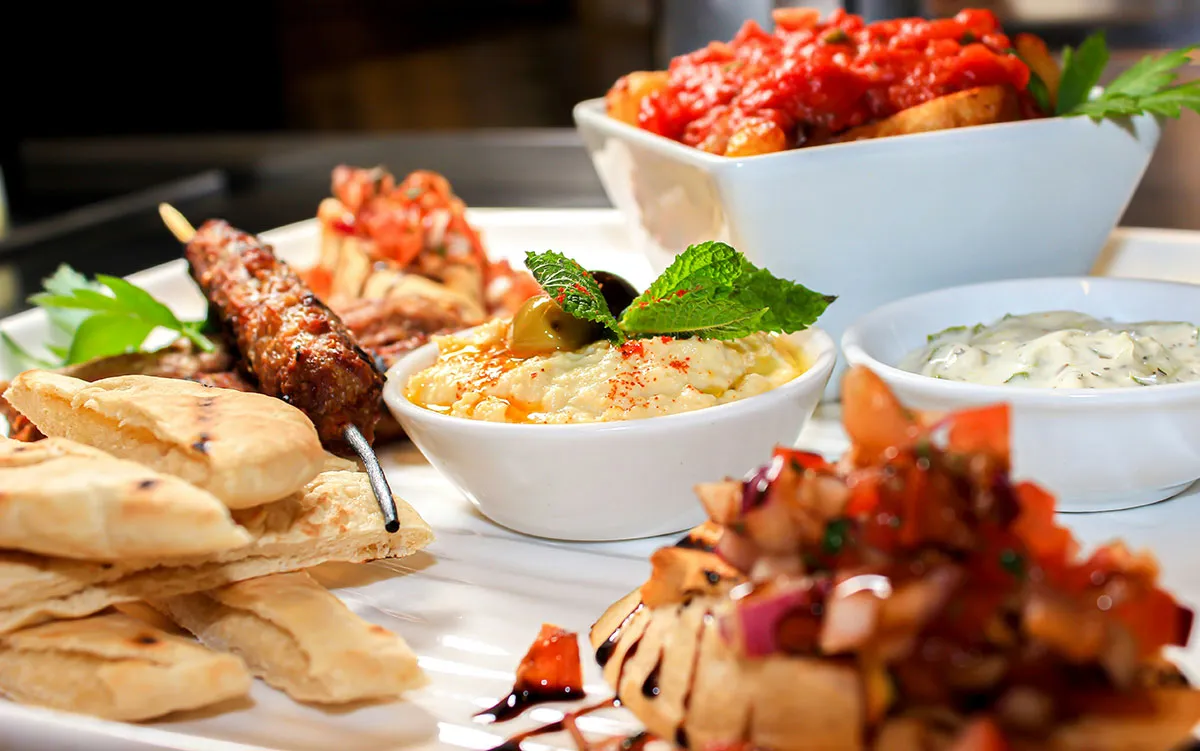 A mezze platter of dips, warm pita and grilled skewers