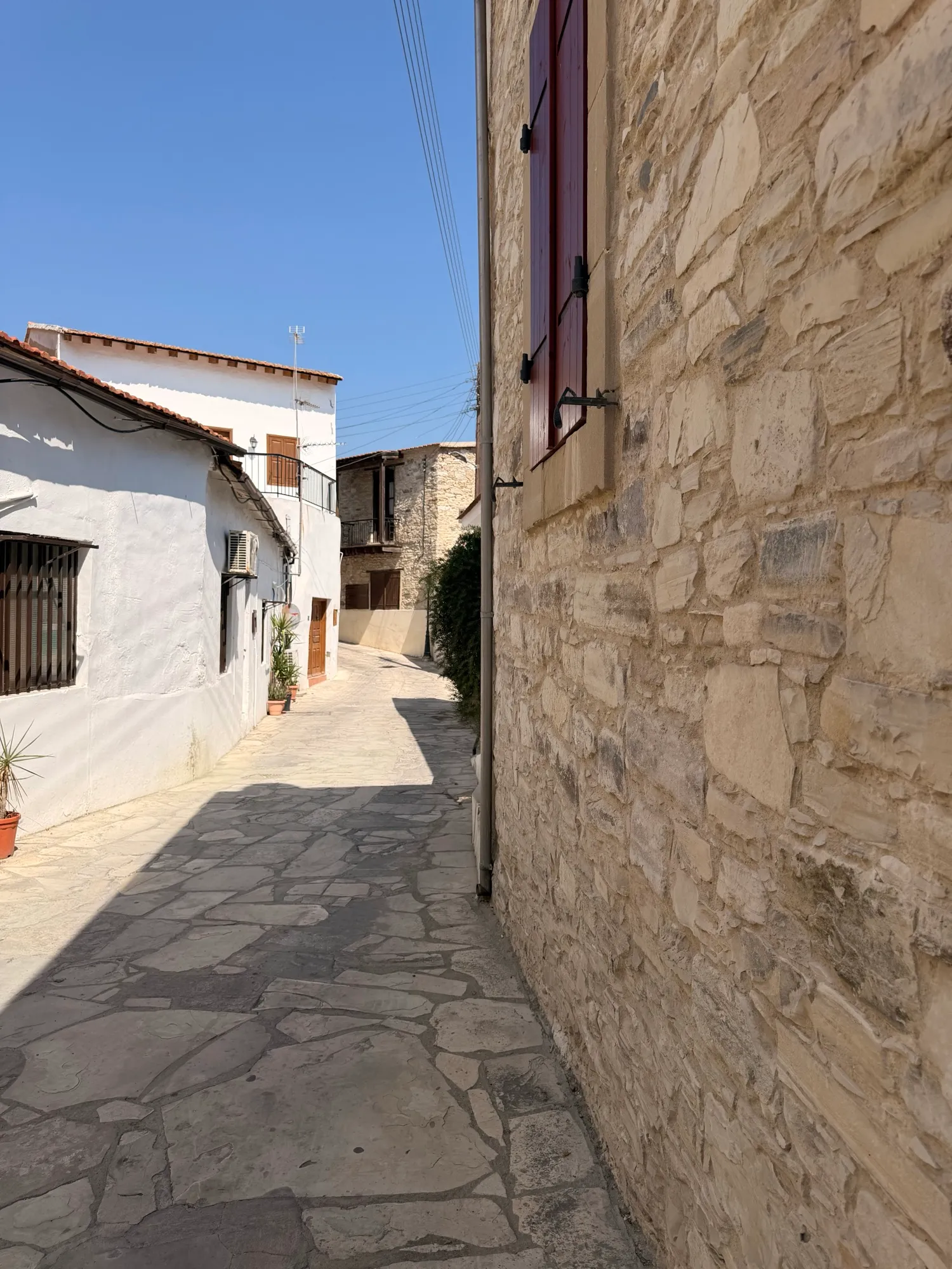 A narrow stone alley with a red shutter