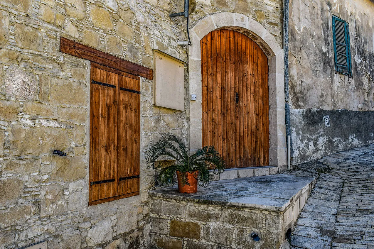 An arched wooden door and shutters on a stone house