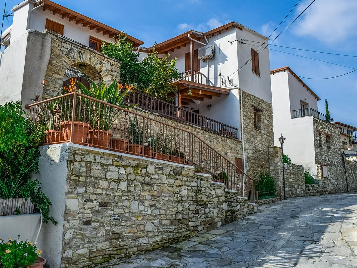 A stone village house with a wooden balcony above cobbled steps